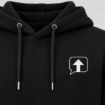 Close-up of the black speech-bubble patch with a white arrow and white stitched border on a black SPEAK//UP hoodie
