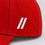 Close-up of white embroidered double slashes on the red SPEAK//UP cap